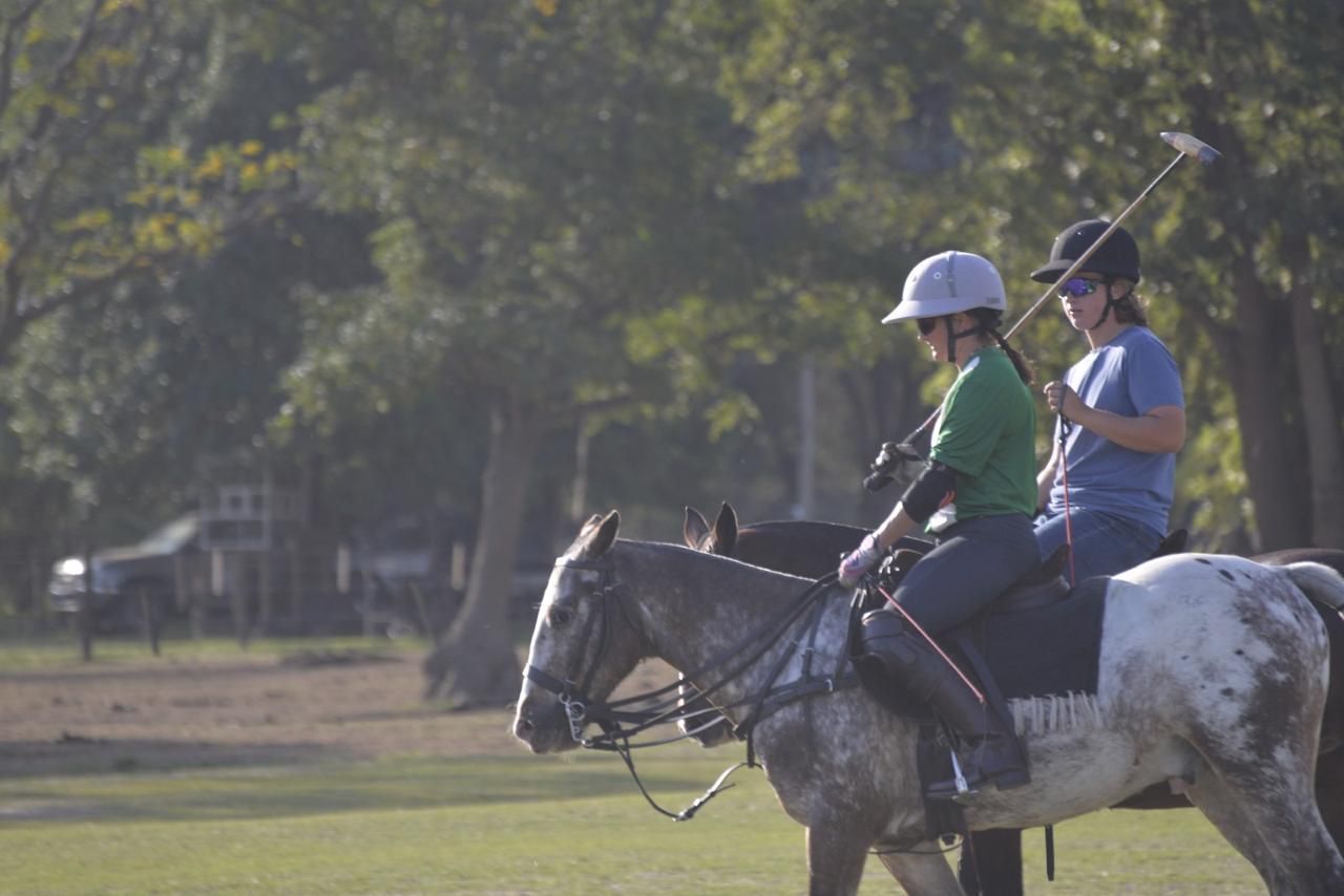 Dos jugadores a caballo, uno al lado del otro, charlando después de la práctica.
